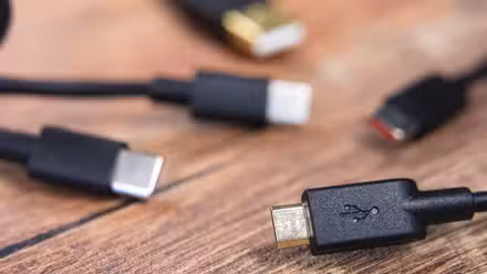 Various USB cable connectors on a wood grain surface.