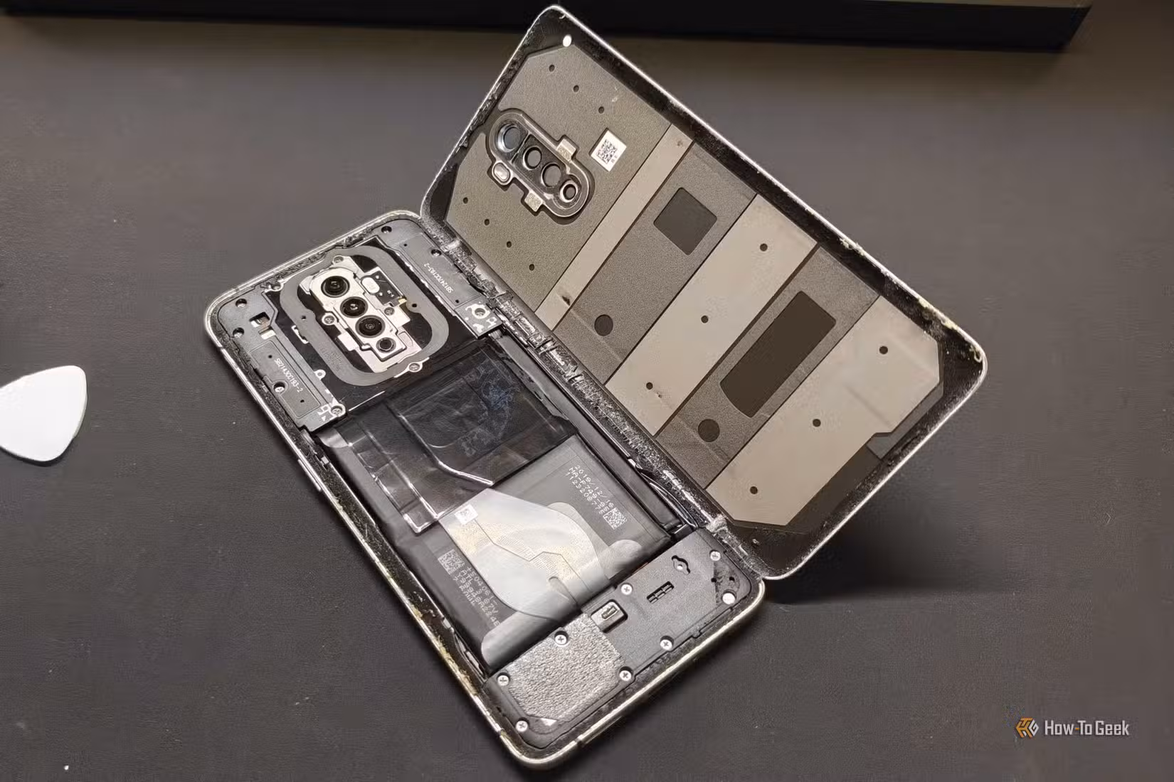 An old Android phone that's been disassembled with the battery exposed.