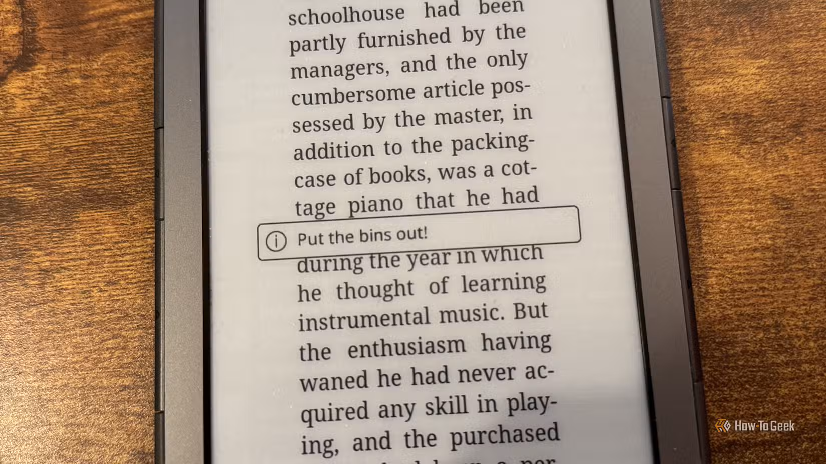 A Kindle 4 with a notification on the screen that reads Put the bins out.