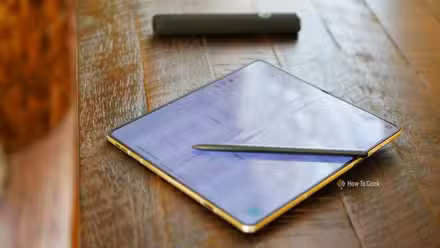 A Moto Pen Ultra on top of an unfolded Motorola Razr Fold displaying a notes app. 