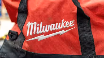 The Milwaukee logo embroidered in white on a red tool bag.