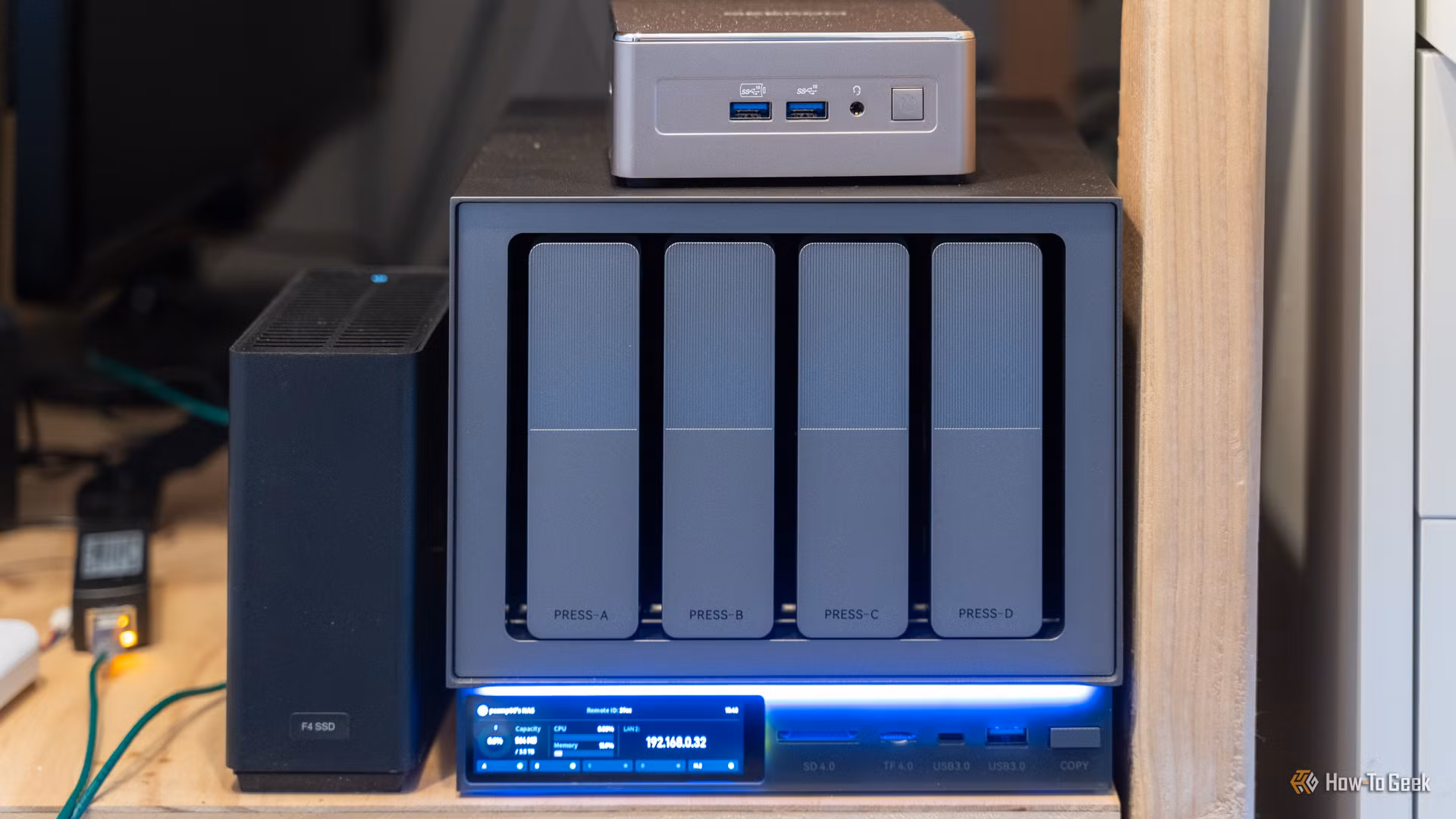 The Zettlab D4 NAS with a Geekom A5 mini PC and TerraMaster F4 SSD NAS on a wooden shelf.