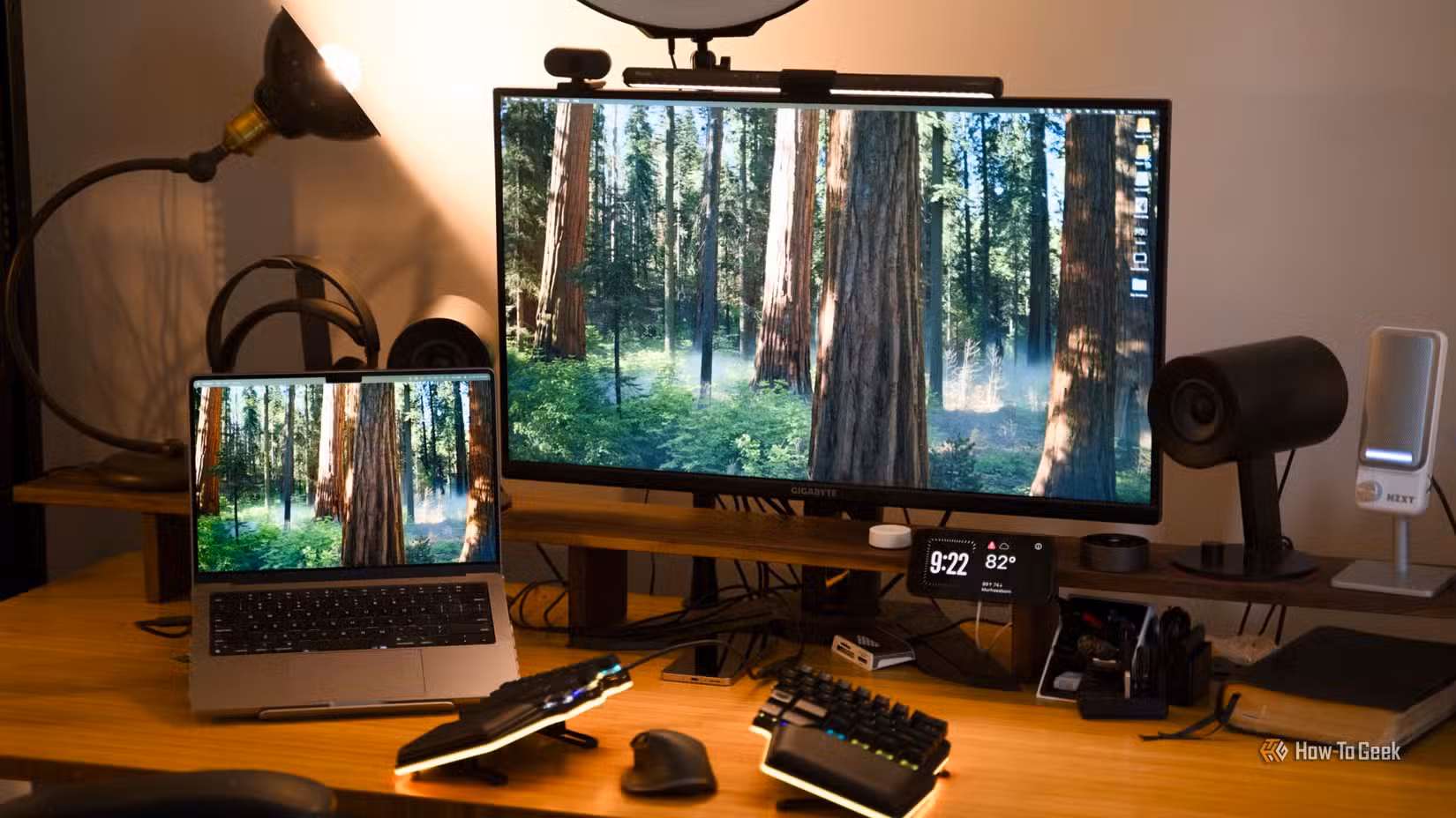 A desk setup featuring a MacBook Pro and a 32-inch 4K monitor with a split keyboard and mouse on the desk.