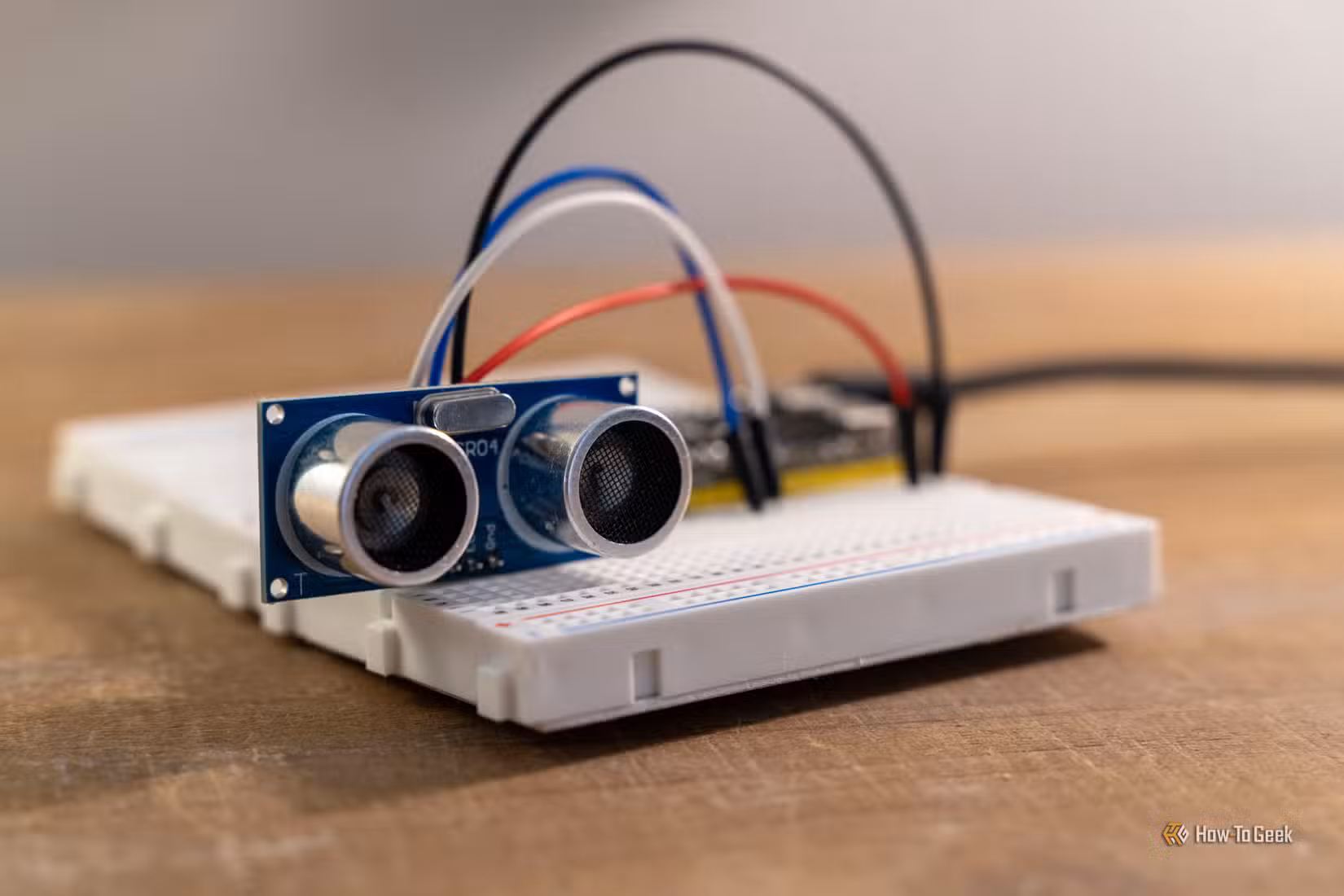 Close-up of an HC-SR04 ultrasonic sensor wired to an ESP32 development board on a breadboard.