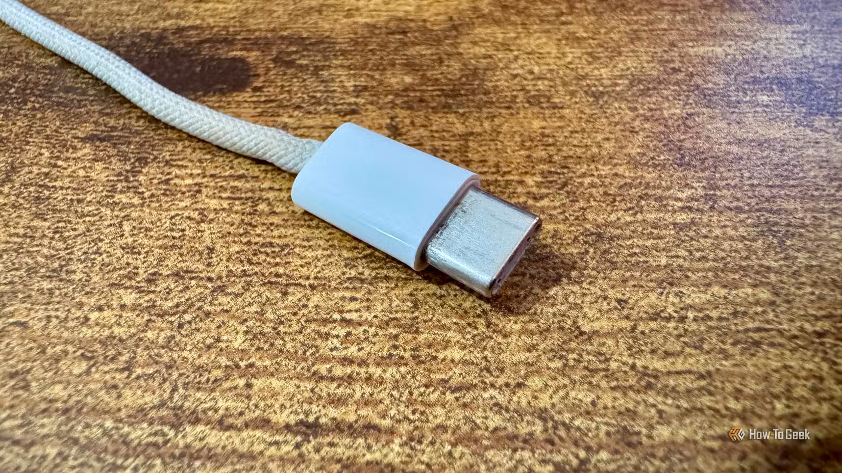 Close up of the Xteink pogo pin charging cable Type-C connector end on a wooden desk.