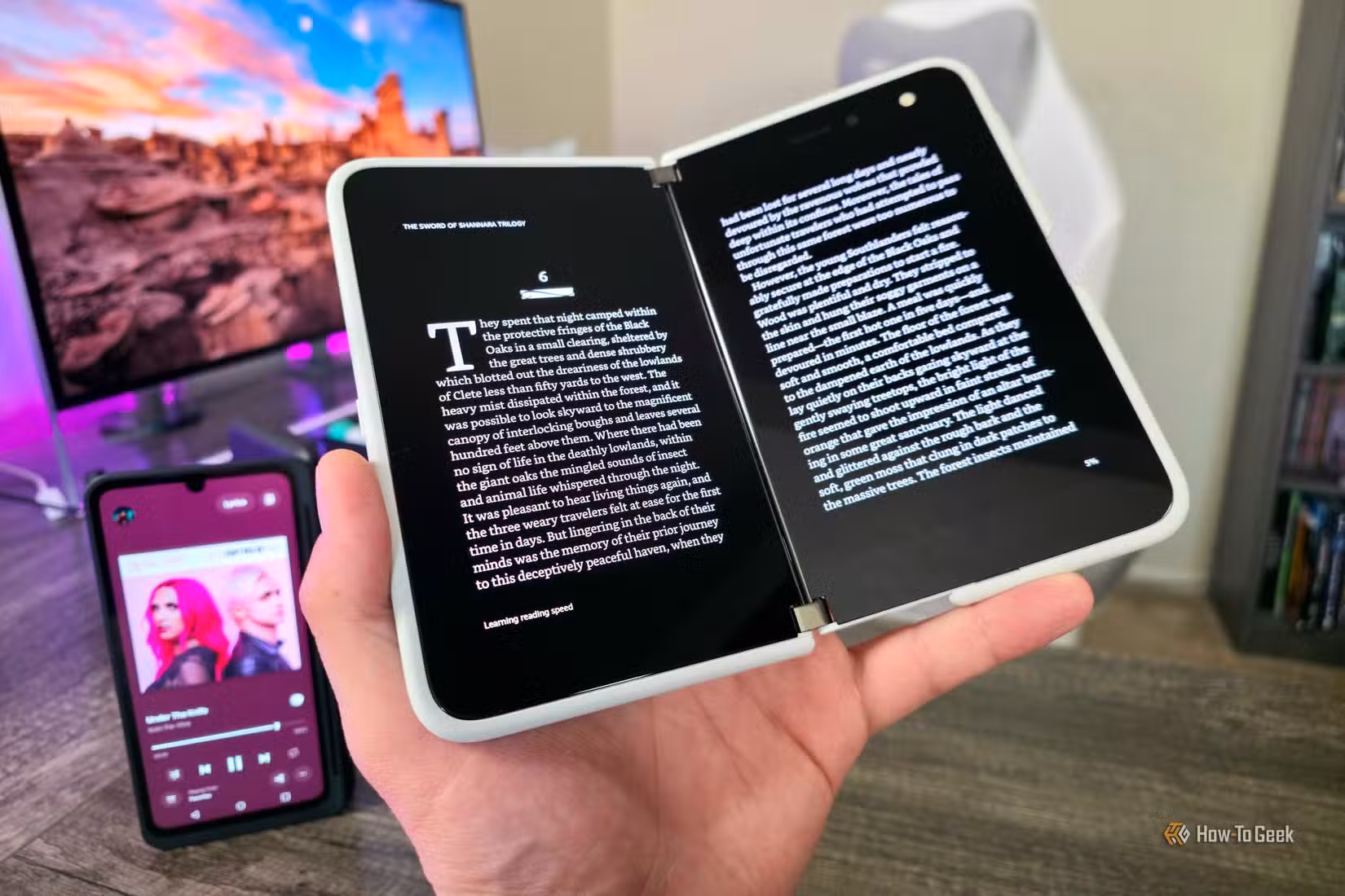 A Surface Duo open with a book displayed on both screens, and an LG V60 ThinQ with its Dual Screen Case in the background.