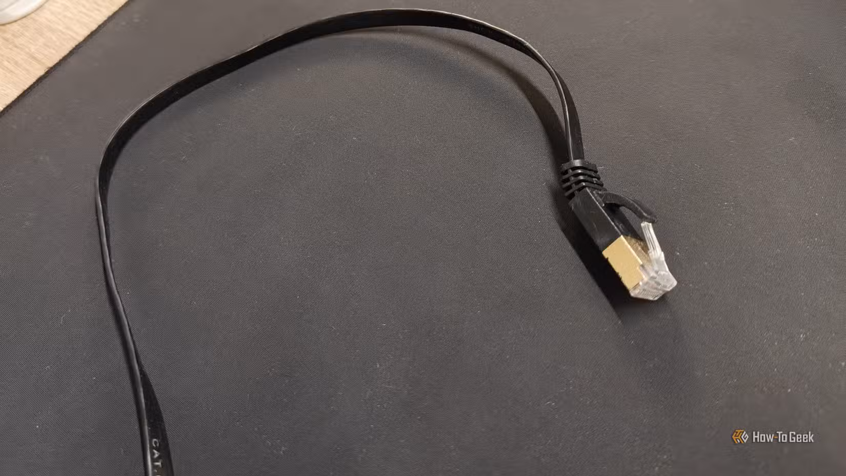 A flat Cat6 Ethernet cable on a black mousepad.