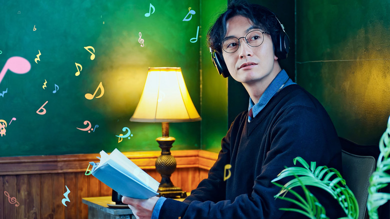 A man holding a book wearing headphones and glasses with musical notes shown next to him.