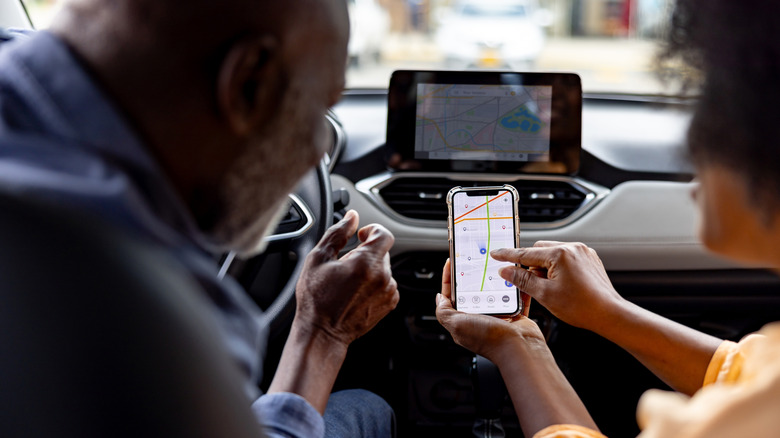 Two people using an iPhone in a car.