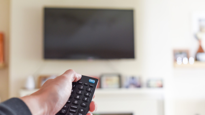 Person pressing power button on TV remote