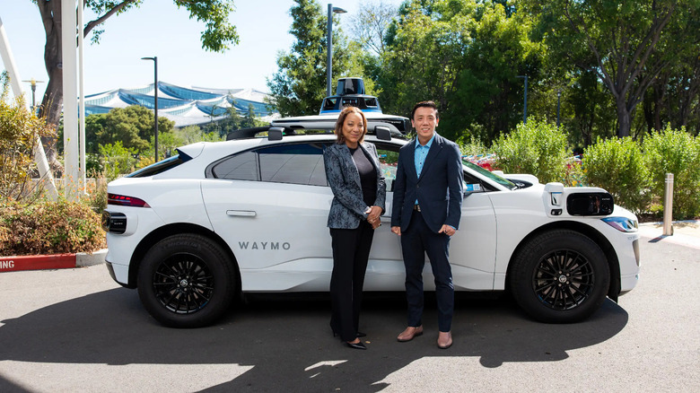 Two people standing in front of a white car