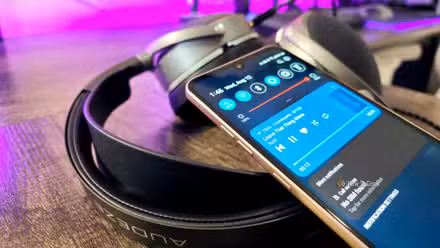 An LG V60 ThinQ smartphone resting on top of Audeze LCD-S20 headphones, showing the 