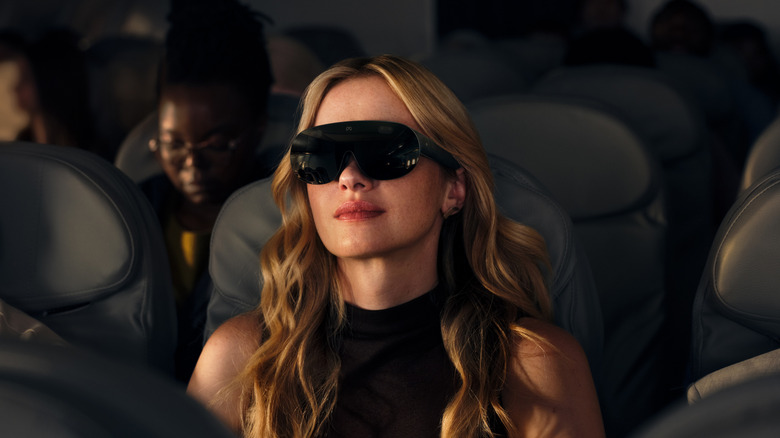 Person wearing blacked-out VR glasses on a plane.