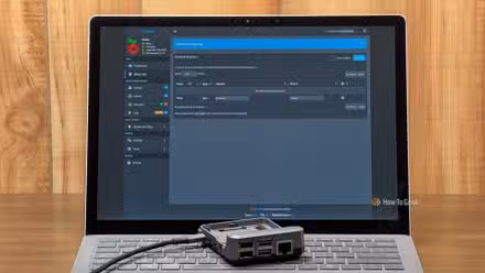A Raspberry Pi laying on the keyboard of a laptop with the Pi-hole dashboard open. 