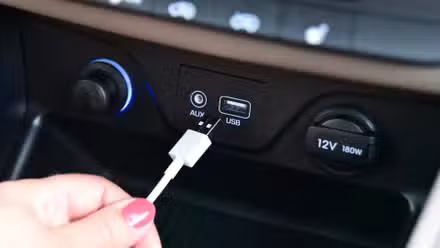 person plugging a USB cable into a car usb port. 
