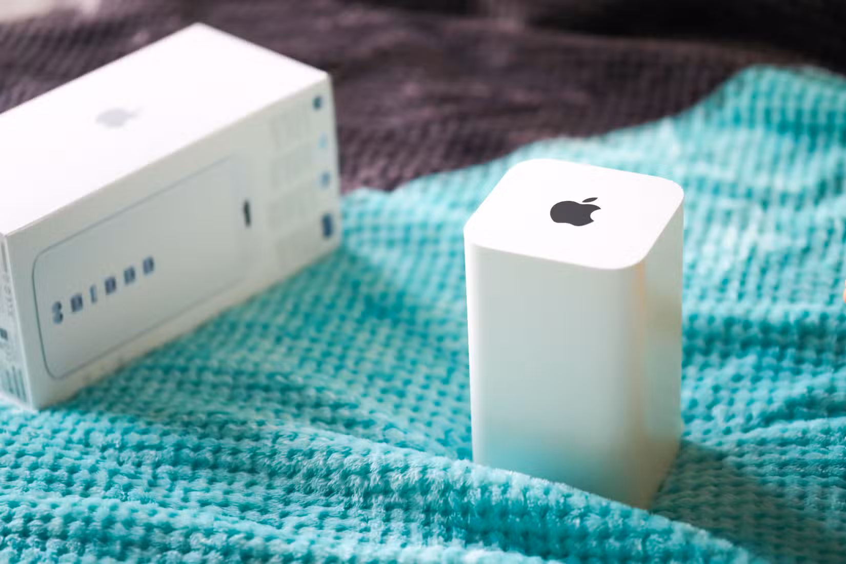The AirPort Time Capsule sitting on a bed next to its box.