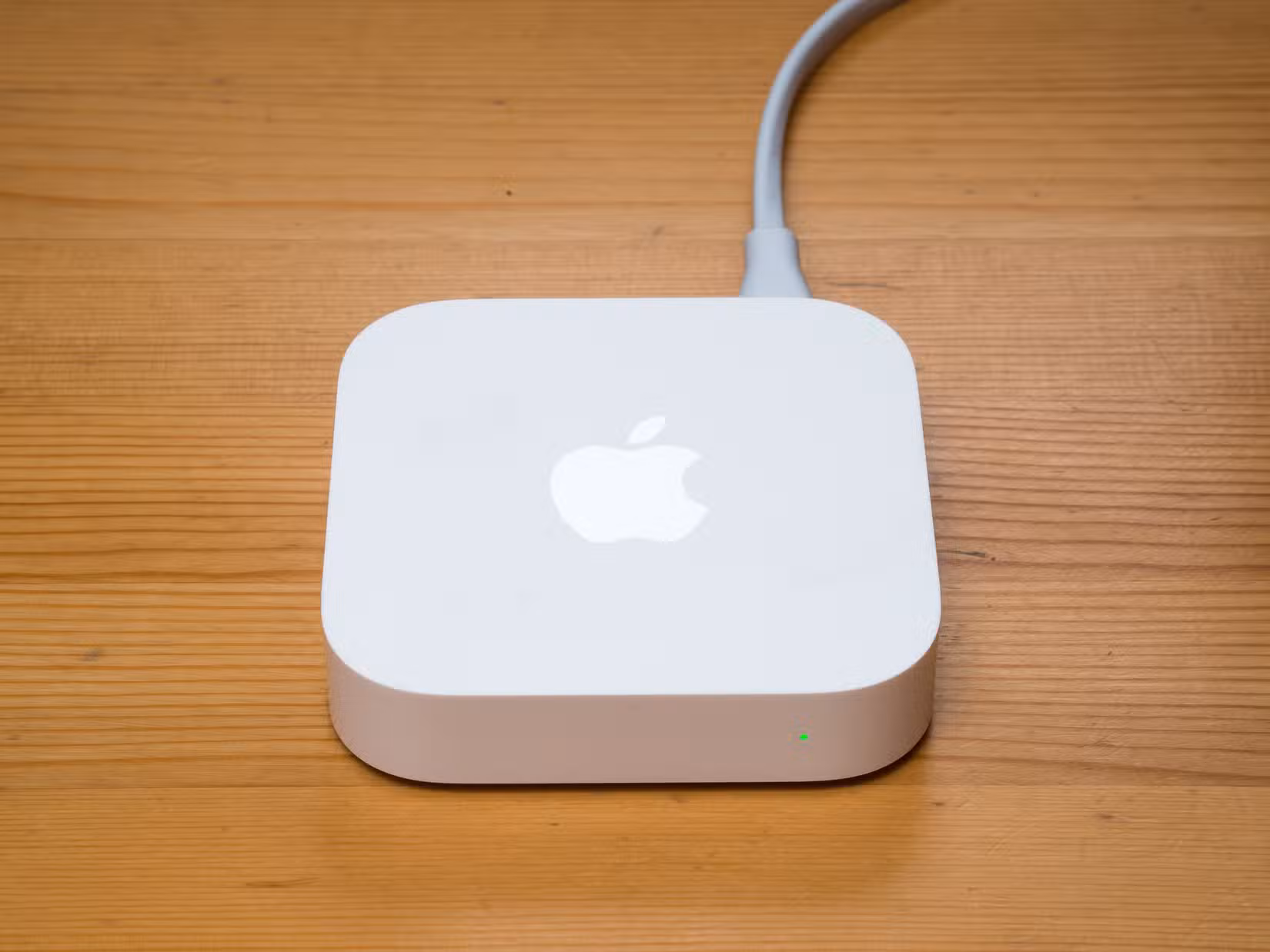 An Apple AirPort Express sitting on a wooden desk.