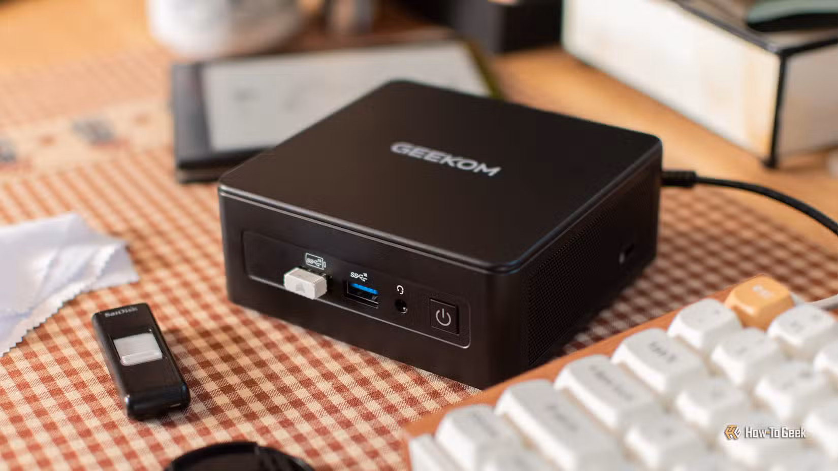 The GEEKOM IT15 mini PC on a desk with a keyboard and ereader.