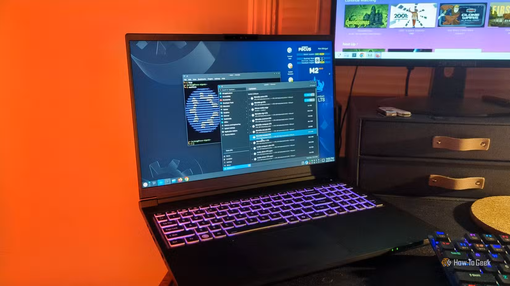 The Kubuntu Focus M2 Gen 6 laptop on a desk with a software updater and Linux terminal open.