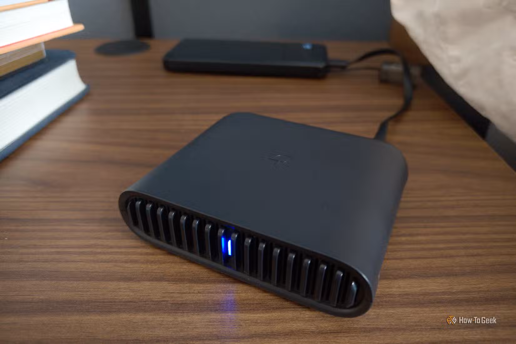 TP-Link travel router on a side table next to books.