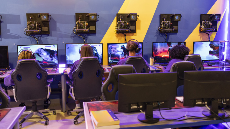 A group of four gamers all sitting at PCs in a line at a competitive gaming event