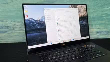 An image of a Windows 11 Dell laptop sitting on a desk. Task Manager is open to the Startup apps tab.